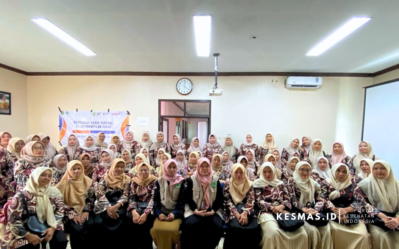 Kader posyandu se-Kecamatan Cibalong berfoto bersama di aula Puskesmas mengenakan seragam batik dan hijab.